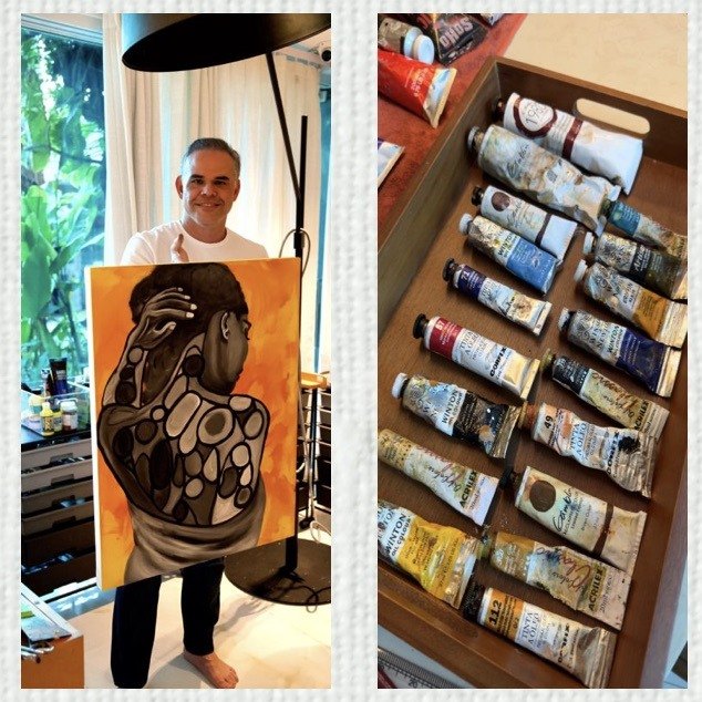 The artist holding a painting, and his tubes of paint